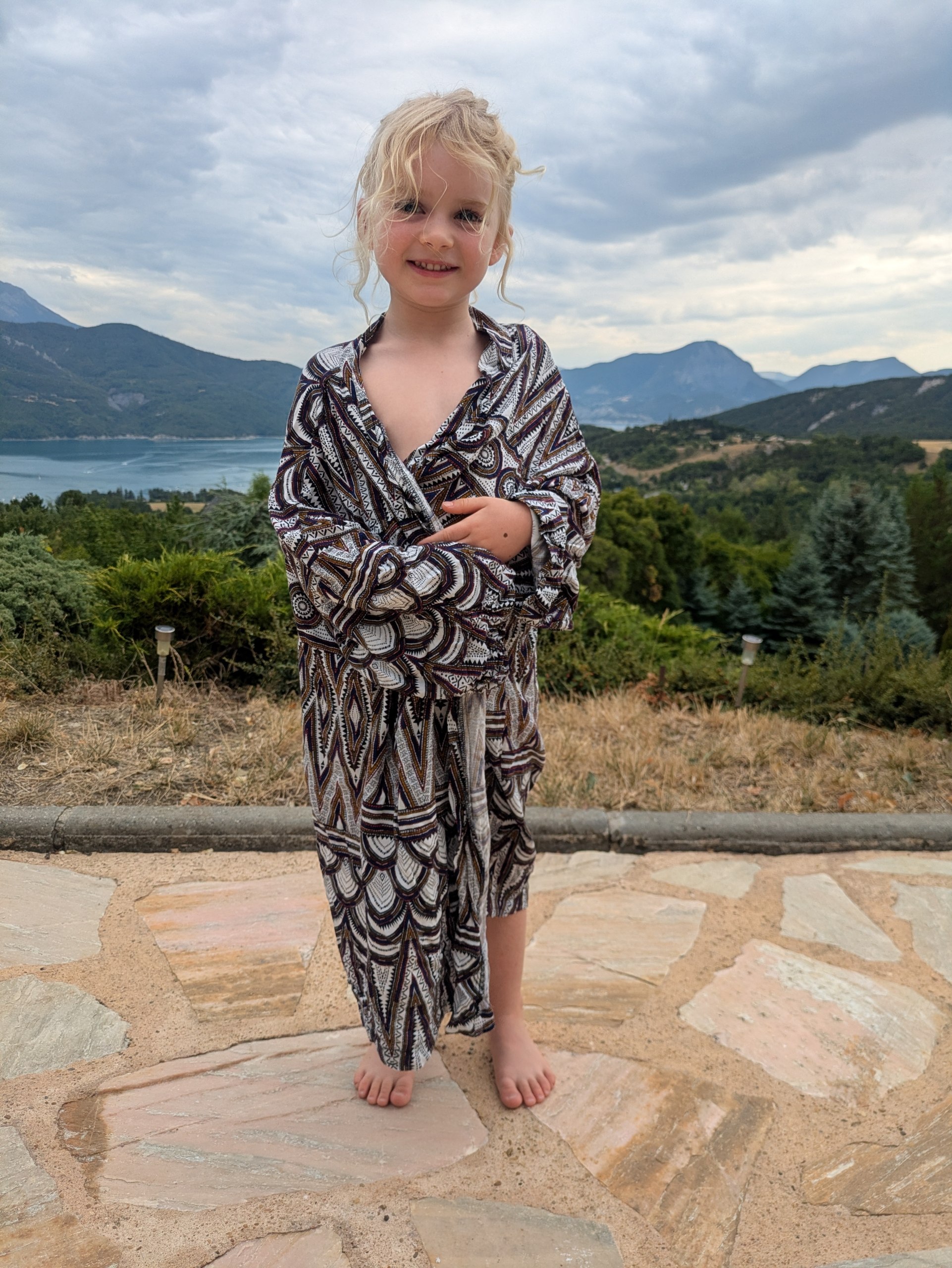 Kimono enfant à motifs graphiques or et ébène, porté face à un lac de montagne